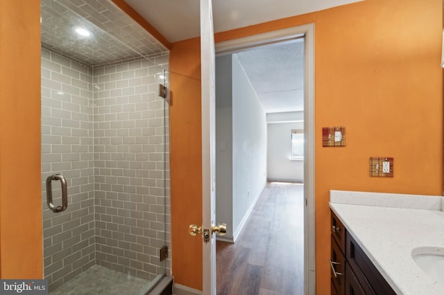 bathroom featuring hardwood / wood-style flooring, vanity, and a shower with shower door