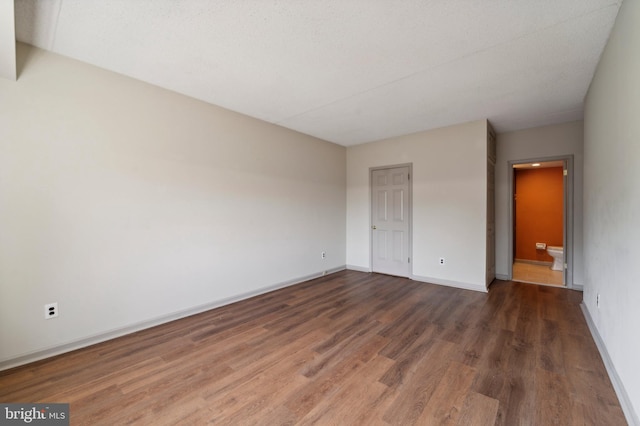 unfurnished bedroom featuring dark wood-type flooring and connected bathroom