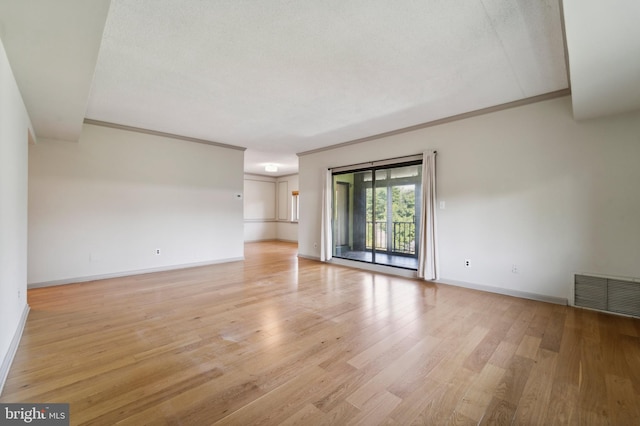 empty room featuring a textured ceiling, light wood-type flooring, and ornamental molding