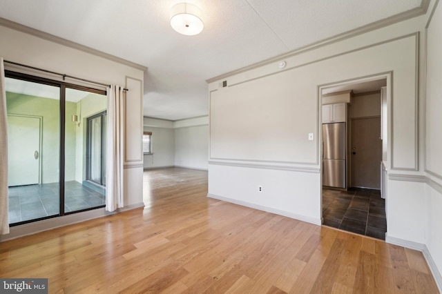 spare room featuring wood-type flooring, ornamental molding, and a textured ceiling