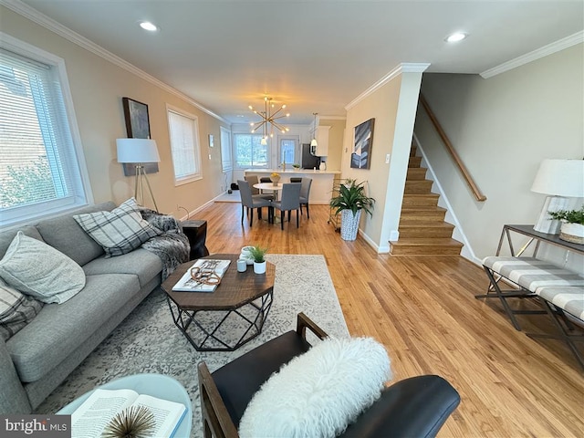 living room with a healthy amount of sunlight, ornamental molding, an inviting chandelier, and light wood-type flooring