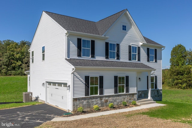 view of front of house featuring central air condition unit, a garage, and a front yard