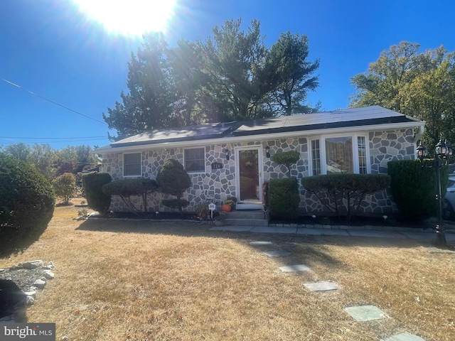 view of front of property featuring solar panels and a front yard