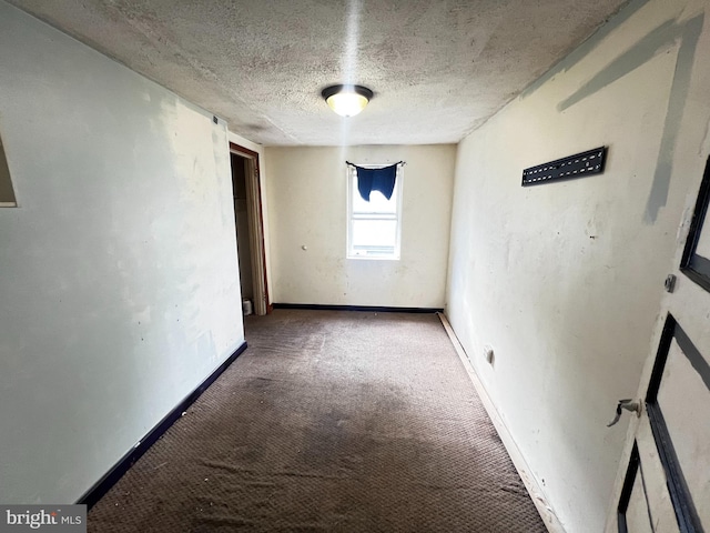 unfurnished room with a textured ceiling and carpet flooring