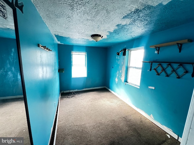 carpeted empty room with a textured ceiling