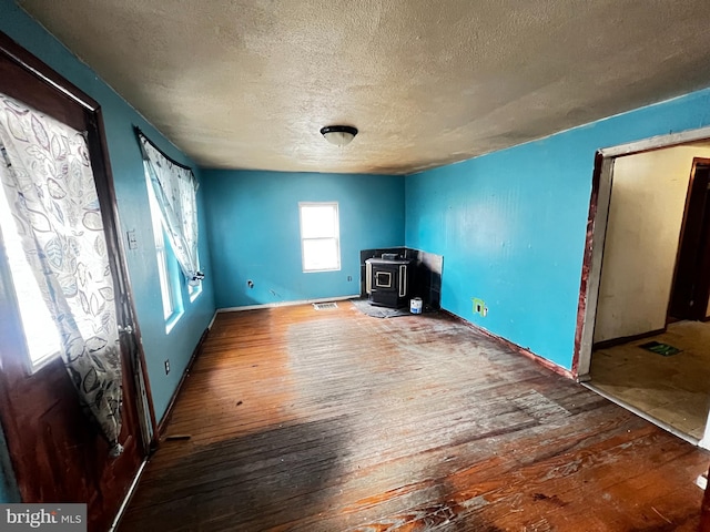 interior space featuring hardwood / wood-style flooring, a textured ceiling, and a wood stove