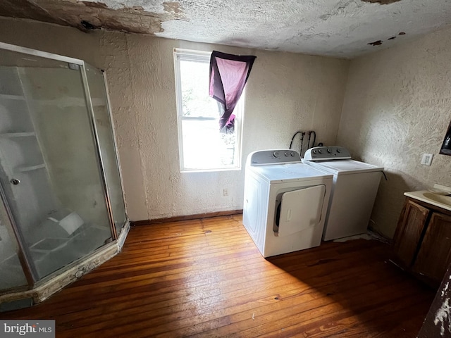 laundry area featuring a textured ceiling, a healthy amount of sunlight, washing machine and clothes dryer, and light hardwood / wood-style flooring