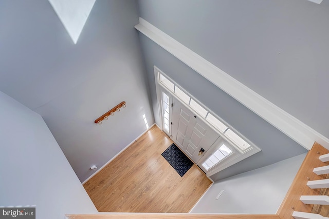 foyer entrance featuring lofted ceiling with skylight and hardwood / wood-style floors