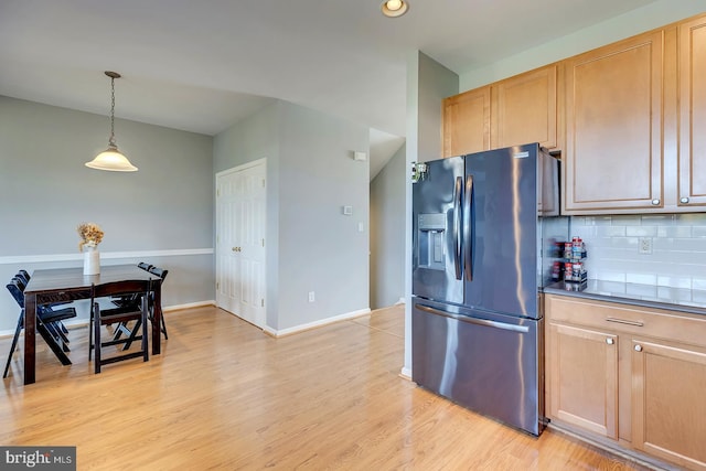 kitchen featuring light brown cabinets, backsplash, stainless steel fridge with ice dispenser, pendant lighting, and light hardwood / wood-style floors