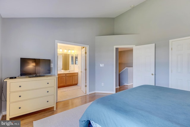 bedroom with high vaulted ceiling, connected bathroom, and light wood-type flooring