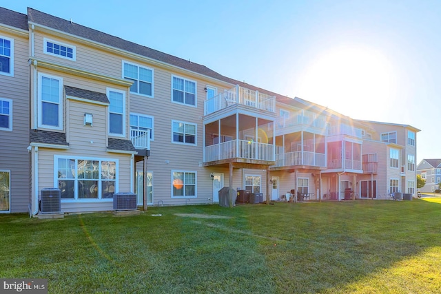 back of property with a balcony, central air condition unit, and a lawn