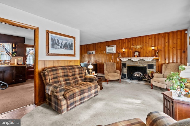 living room featuring wood walls, a wall unit AC, carpet, and a stone fireplace