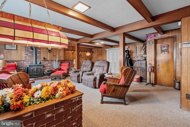 carpeted living room featuring beamed ceiling, wood walls, and a wood stove