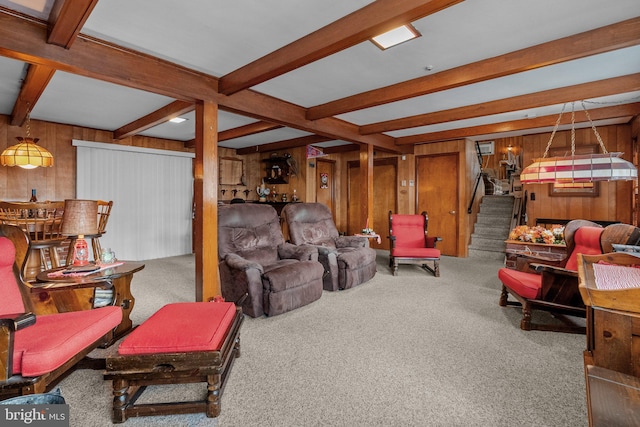 living room featuring beamed ceiling, wood walls, and carpet floors