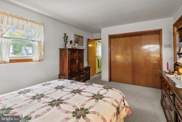 bedroom featuring a baseboard radiator, a closet, and light colored carpet