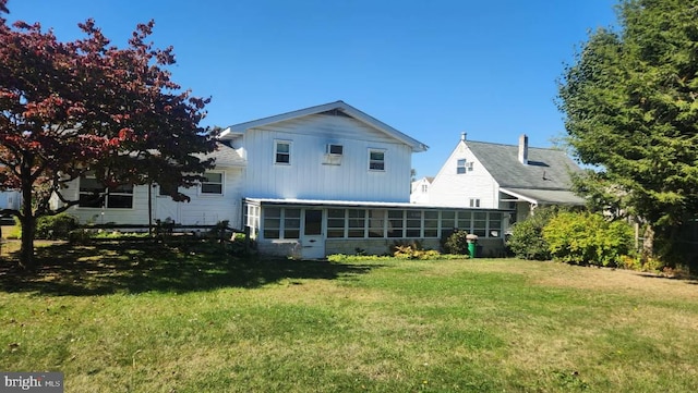 rear view of house featuring a sunroom and a yard