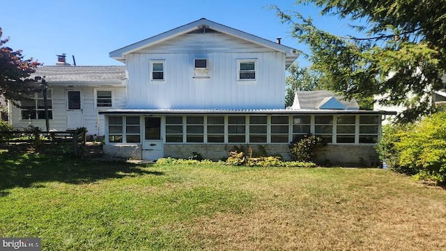 rear view of property featuring a sunroom and a lawn