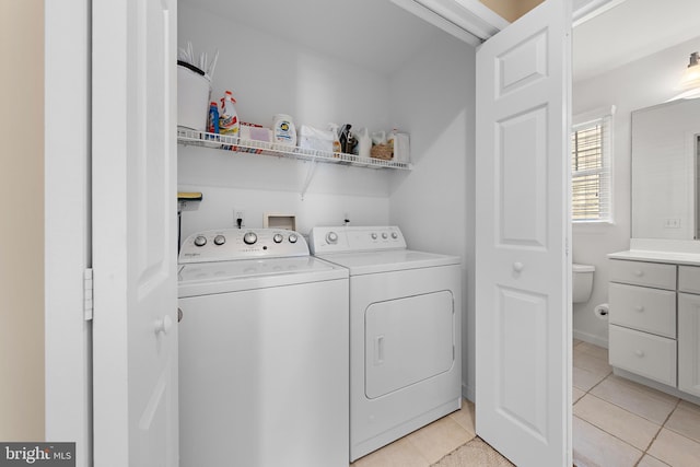 clothes washing area featuring washer and clothes dryer and light tile patterned floors