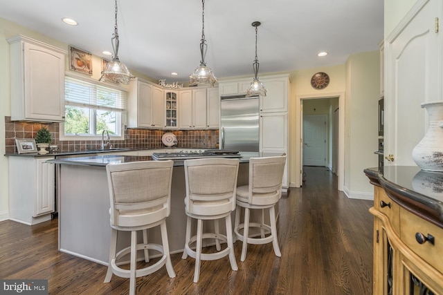 kitchen with decorative backsplash, dark hardwood / wood-style flooring, a center island, and decorative light fixtures