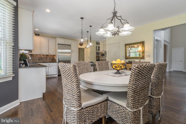 dining area with plenty of natural light, dark hardwood / wood-style flooring, sink, and an inviting chandelier