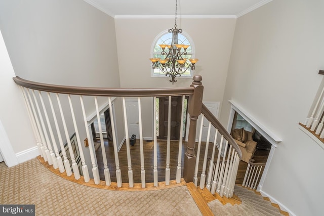 staircase with hardwood / wood-style flooring, ornamental molding, and an inviting chandelier