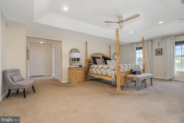 carpeted bedroom featuring a tray ceiling and ceiling fan