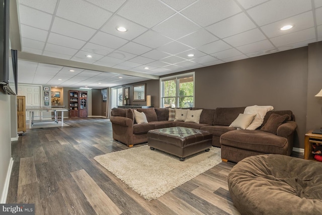 living room with a paneled ceiling and dark wood-type flooring