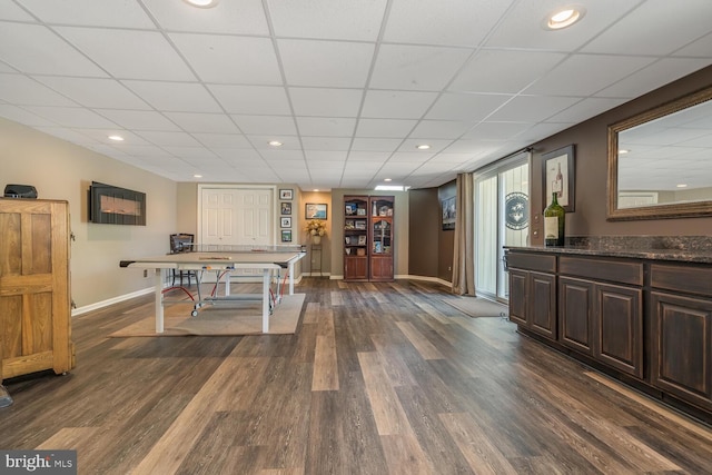 game room featuring dark hardwood / wood-style flooring and a drop ceiling