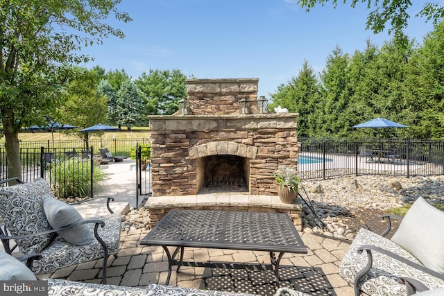 view of patio featuring an outdoor stone fireplace and a fenced in pool