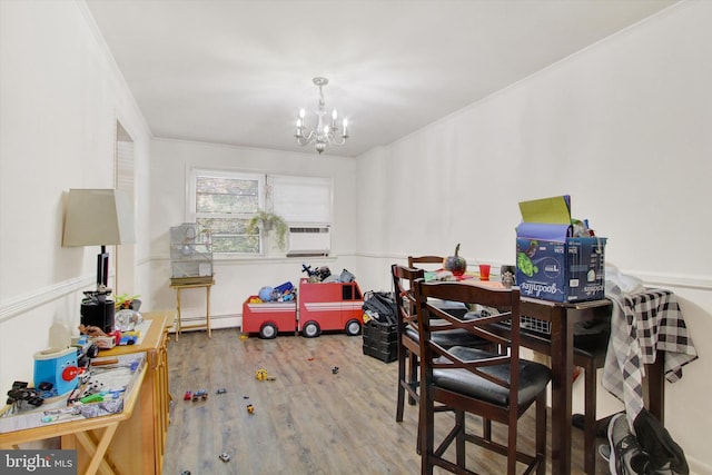 dining room featuring cooling unit, baseboard heating, hardwood / wood-style flooring, an inviting chandelier, and crown molding