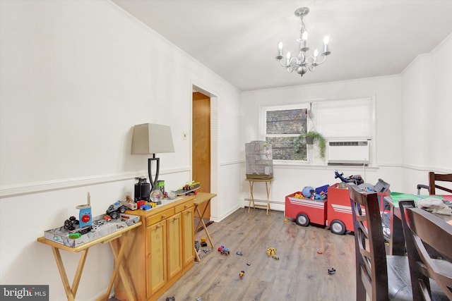 dining area with light hardwood / wood-style floors, a chandelier, cooling unit, a baseboard radiator, and ornamental molding