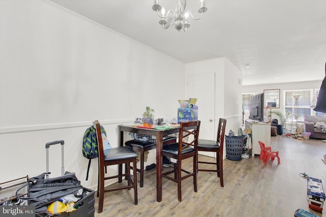 dining area with ornamental molding, a chandelier, and light hardwood / wood-style floors