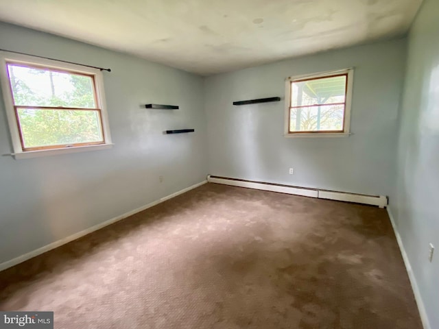 carpeted spare room featuring baseboard heating and a wealth of natural light