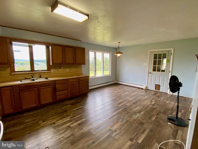 kitchen with tasteful backsplash, baseboard heating, dark hardwood / wood-style floors, sink, and hanging light fixtures