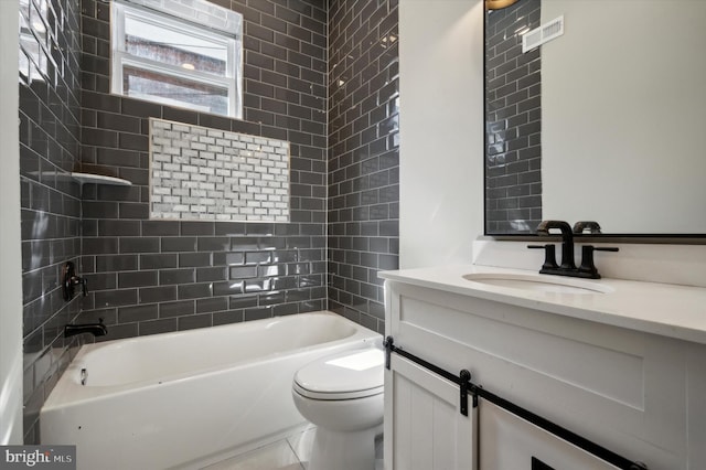 full bathroom featuring tile patterned flooring, tiled shower / bath, vanity, and toilet