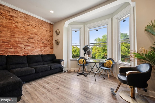 living room with ornamental molding, brick wall, and light hardwood / wood-style flooring