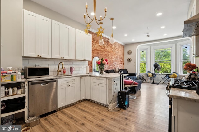 kitchen featuring white cabinets, appliances with stainless steel finishes, hanging light fixtures, and light hardwood / wood-style flooring