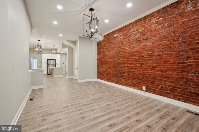 unfurnished dining area with brick wall, light hardwood / wood-style floors, and ornamental molding