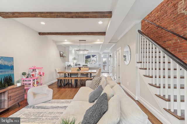 living room with a chandelier, wood-type flooring, brick wall, and beam ceiling