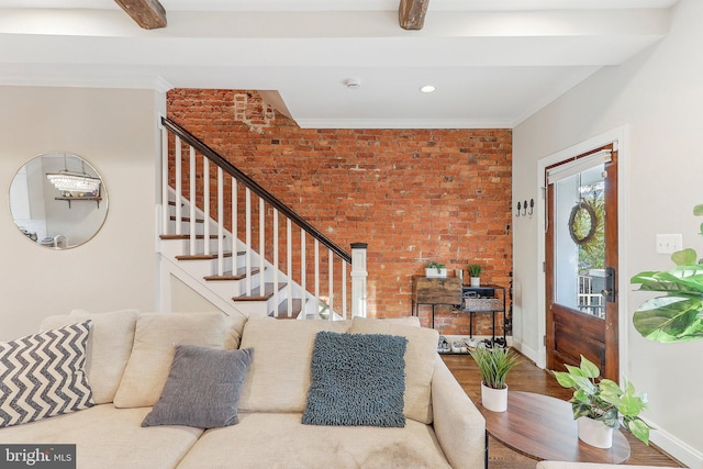 living room with brick wall, wood-type flooring, ornamental molding, and beam ceiling