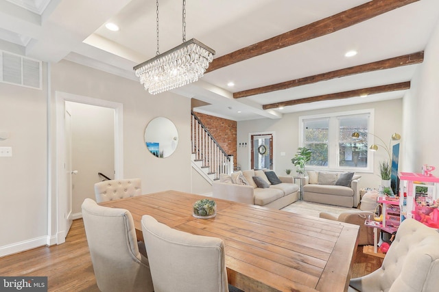 dining area with a notable chandelier, light hardwood / wood-style floors, and beam ceiling