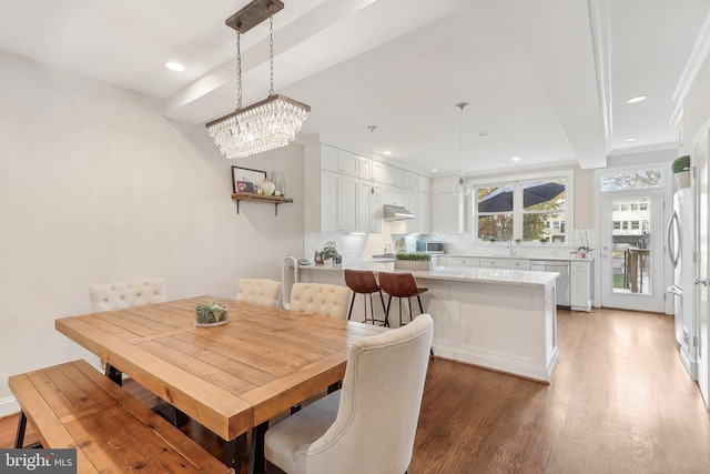 dining area with beam ceiling, dark hardwood / wood-style flooring, an inviting chandelier, and sink