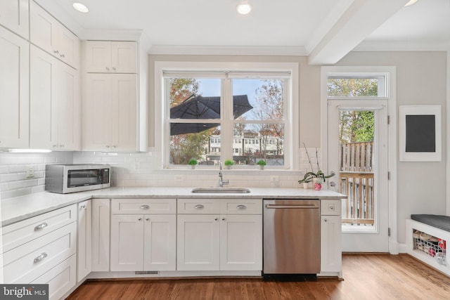 kitchen with appliances with stainless steel finishes, white cabinetry, plenty of natural light, and sink