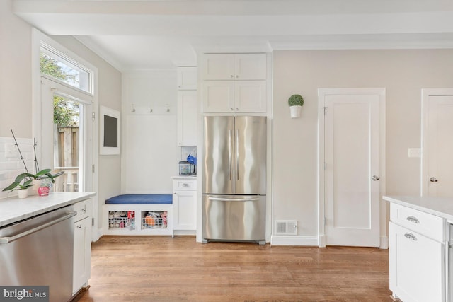 kitchen featuring white cabinets, appliances with stainless steel finishes, light hardwood / wood-style floors, and crown molding