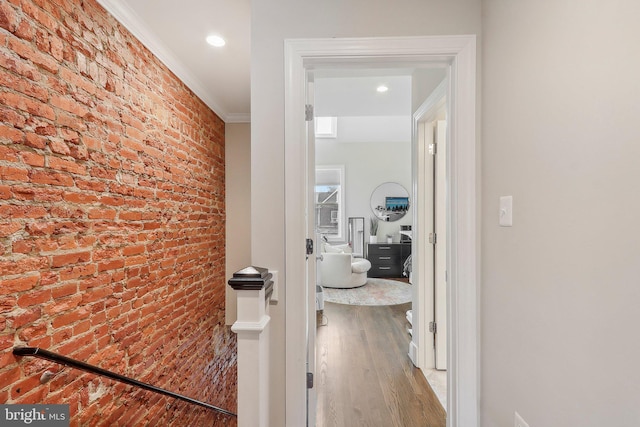 hall with ornamental molding, brick wall, and wood-type flooring