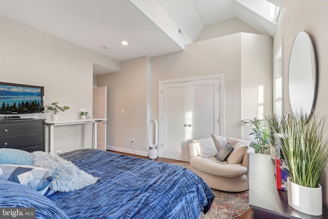 bedroom with hardwood / wood-style flooring and lofted ceiling with skylight