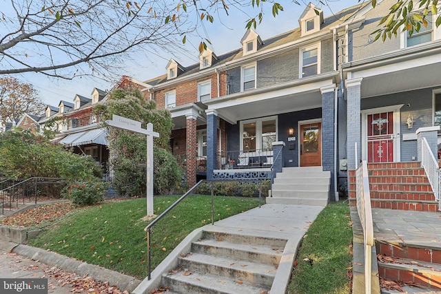 townhome / multi-family property featuring covered porch and a front yard