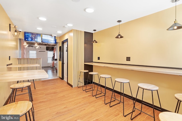 kitchen with light hardwood / wood-style flooring, hanging light fixtures, and a kitchen bar