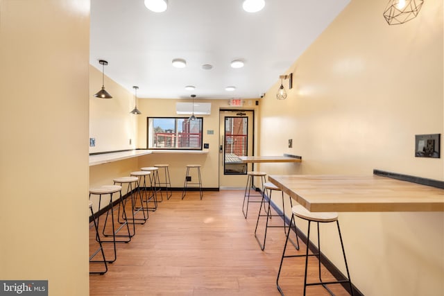 kitchen featuring wood counters, decorative light fixtures, light hardwood / wood-style floors, and a breakfast bar