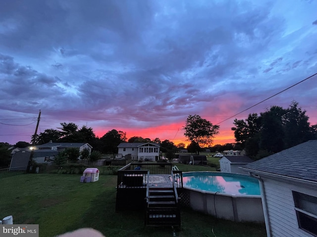 pool at dusk with a yard and a deck